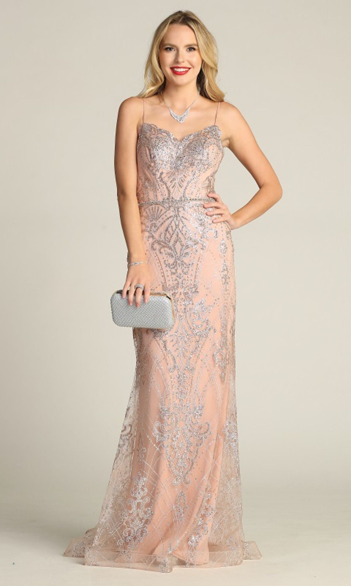 A woman wearing the Lace-Up Long Glitter Prom Dress (Chicas CHF3053) in blush pink, floor-length with silver details, holds a silver clutch and necklace while posing against a plain background.